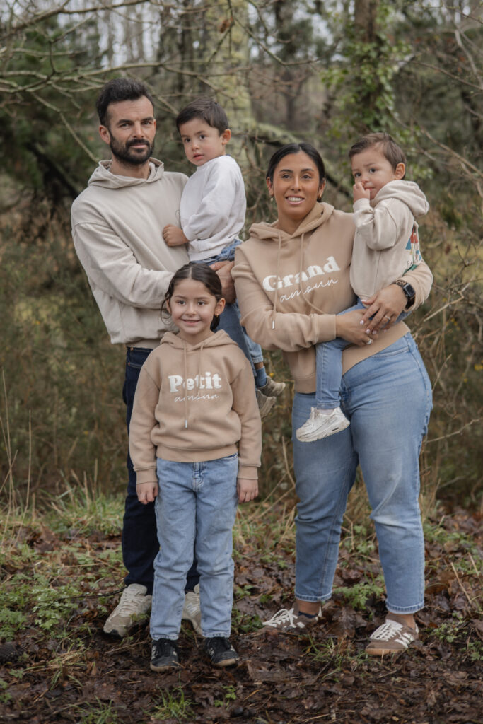 Famille réunie en forêt, parents et enfants posant ensemble en lumière naturelle.