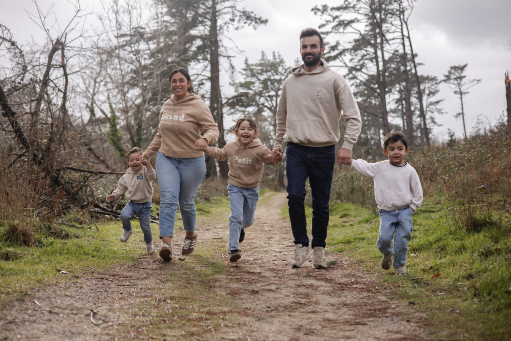 Famille marchant main dans la main en forêt, séance photo lifestyle en Vendée.