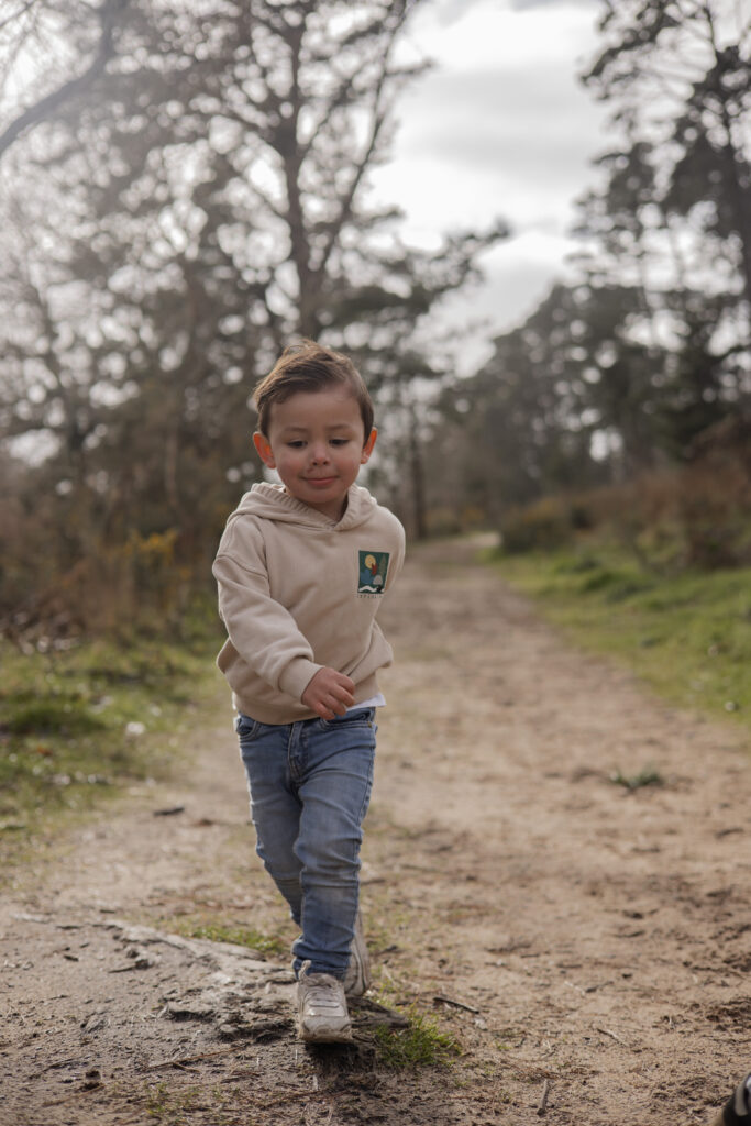 Photographie d'un enfant marchant sur un sentier en forêt, scène douce et spontanée a Aizenay en Vendée.