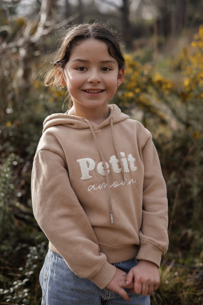 Portrait d’un enfant souriant en forêt, photographie lifestyle en lumière naturelle.