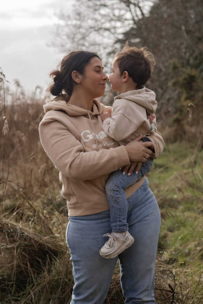 Parent tenant son enfant et partageant un bisou, scène familiale douce en pleine nature.