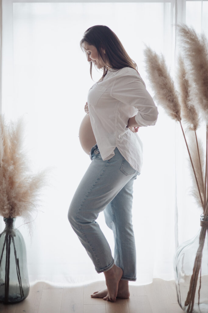 Profil de femme enceinte en lumière naturelle, séance grossesse lifestyle en intérieur en Vendée.