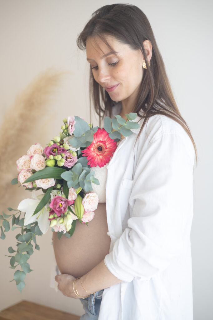 portait d'une femme enceinte tenant un bouquet de fleurs dans les mains en séance a domicile en Vendée