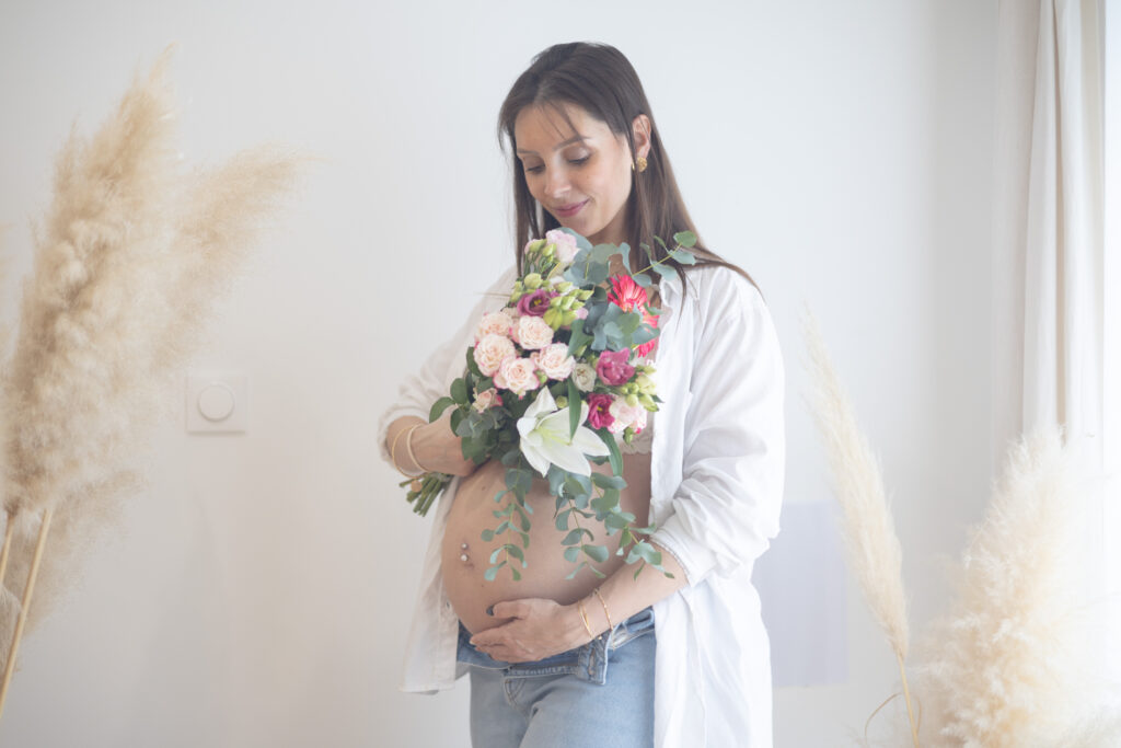 Séance grossesse en intérieur, a domicile ,femme enceinte tenant un bouquet, photographie lifestyle à Bretignolles sur Mer en Vendée.