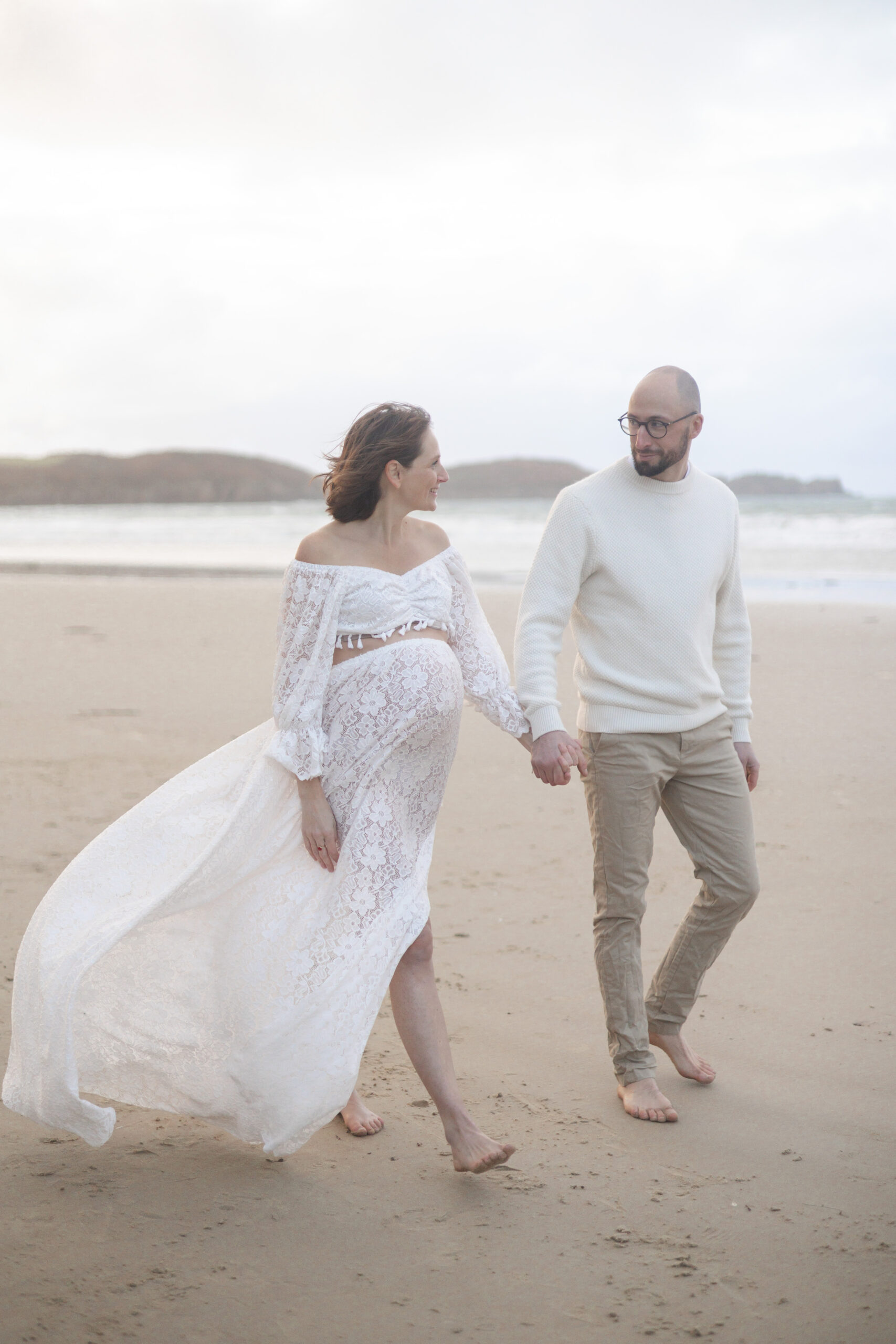 couple marchant main dans la main au bord de l'océan lors d'une séance photo grossesse a la plage des Sables d'Olonnes