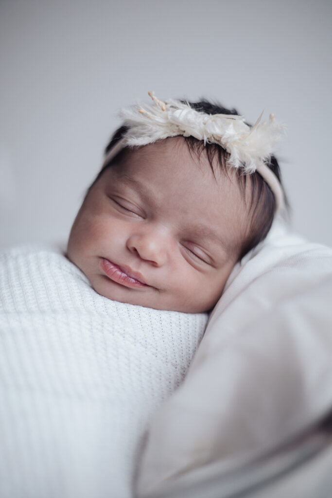 Nouvelle‑née emmaillotée dans un seau, photographie en lumière douce et ambiance cocooning.